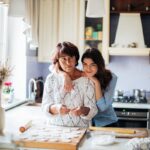 A heartwarming scene of a mother and daughter bonding while baking in their kitchen.
